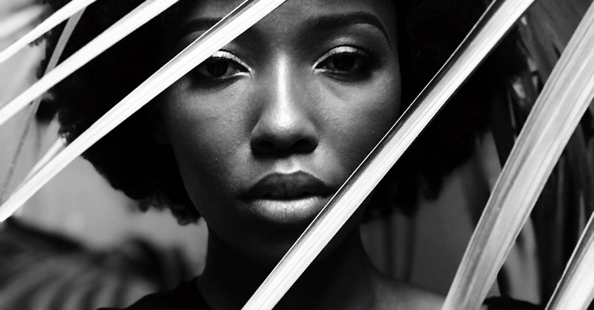 Elegant black and white portrait of a woman behind leaves, capturing natural beauty.