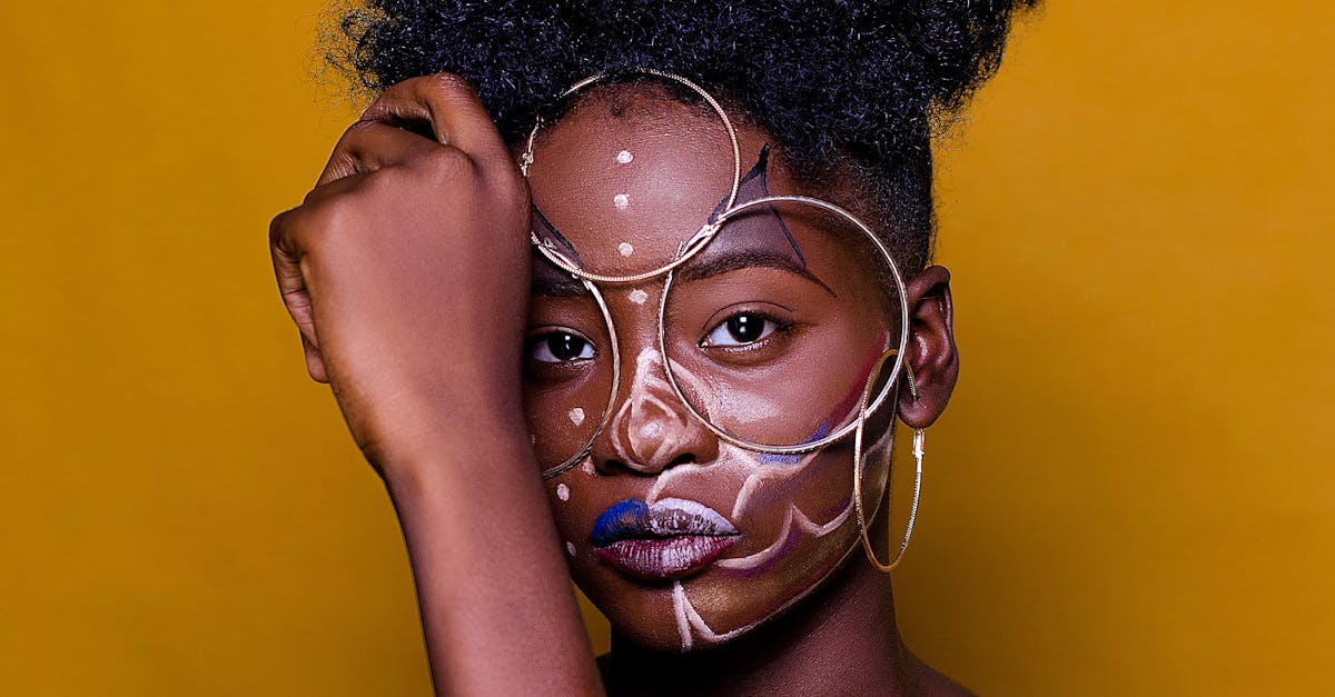 Artistic portrait of a woman with unique face paint against a vibrant backdrop.