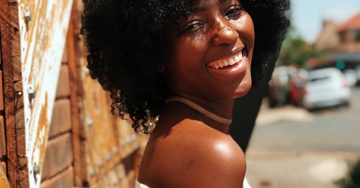 Joyful woman with afro hair smiling outdoors in Johannesburg. Bright and vibrant atmosphere.