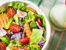 Colorful fresh vegetable salad with cherry tomatoes in a white bowl.