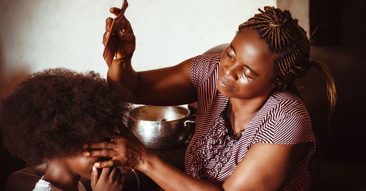 A loving mother combs her son's afro hair at their home in Abuja, Nigeria, showcasing family care and connection.
