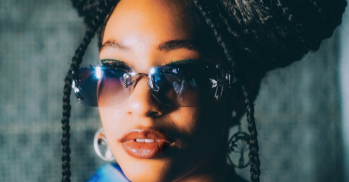 Fashionable woman in afro braids and sunglasses, showcasing urban style outdoors.
