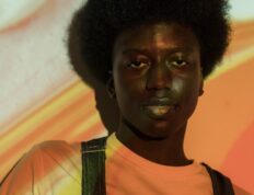 Close-up portrait of a young man with unique Afro hairstyle under creative lighting.