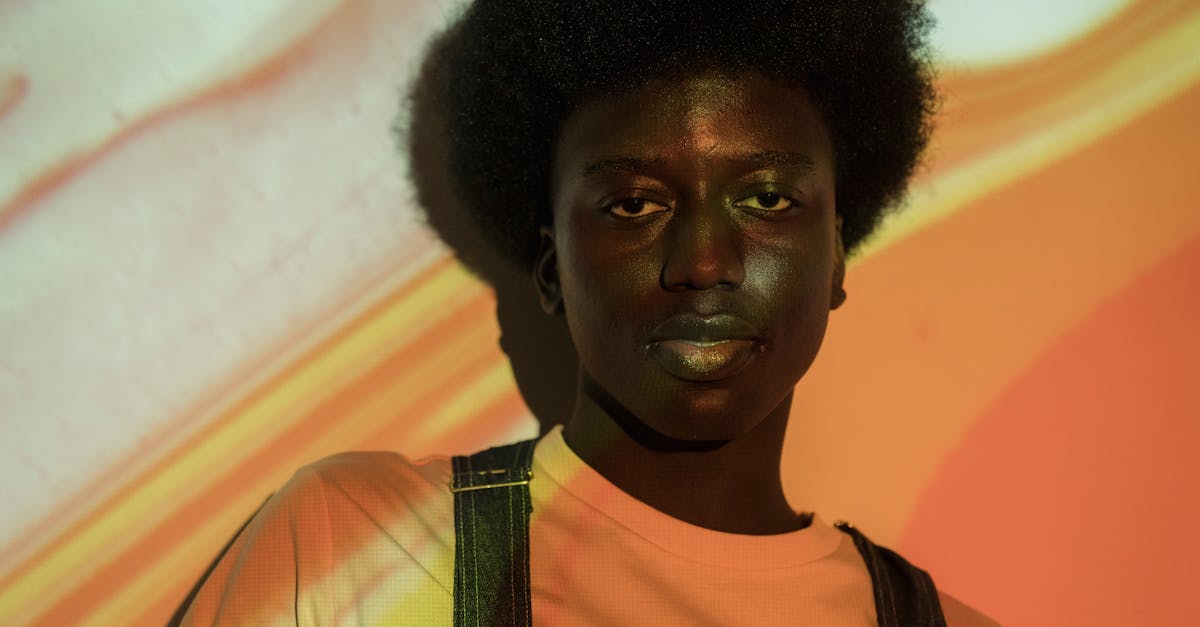 Close-up portrait of a young man with unique Afro hairstyle under creative lighting.