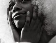 Dramatic black and white portrait of a fashion model with white afro hairstyle, exuding elegance and style.
