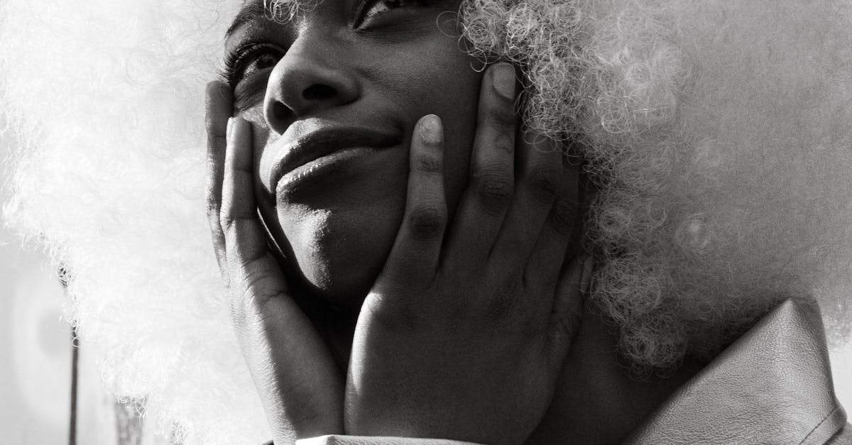 Dramatic black and white portrait of a fashion model with white afro hairstyle, exuding elegance and style.